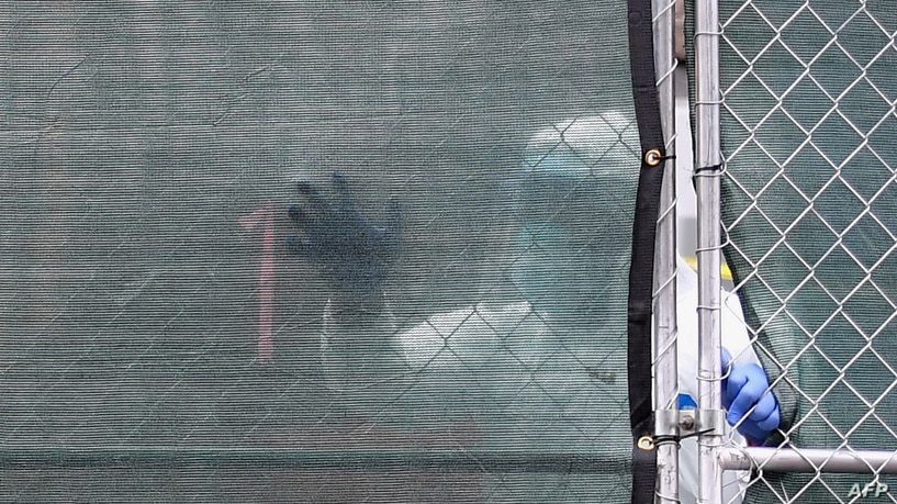عامل في الحقل الطبي يمر أمام مدخل شاحنة مبردة - كورنا