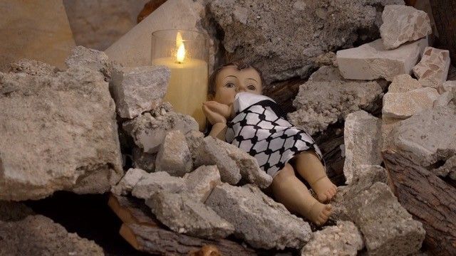 مجسم الطفل يسوع المسيح بالكوفية الفلسطينية وضعت بدلاً من زينة عيد الميلاد بين الركام.