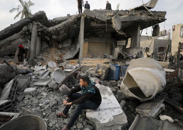 فلسطينيون يتفقدون منزلا مدمرا في دير البلح، وسط قطاع غزة
