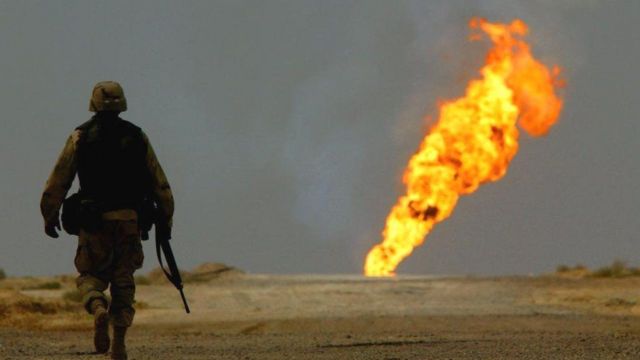 جندي أمريكي يسير قرب حقل نفط مشتعل في جنوبي العراق