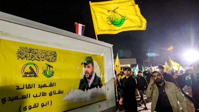 أعضاء بقوات الحشد الشعبي يسيرون خلف عربة تحمل جثمان