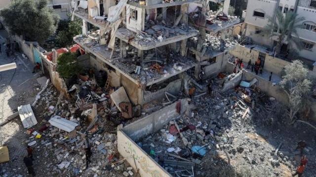 فلسطينيون يتفقدون موقع غارة إسرائيلية على أحد المنازل في رفح جنوبي قطاع غزة - 25 مارس/آذار 2024