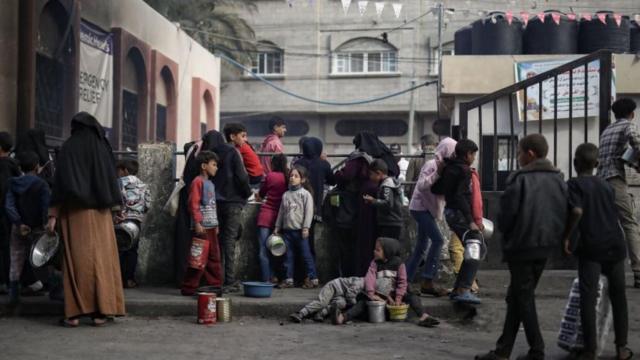 فلسطينيون نازحون في رفح جنوب قطاع غزة، يتجمعون لجمع الطعام الذي تبرعت به مجموعة خيرية قبل الإفطار، في شهر رمضان، 14 مارس/آذار 2024.