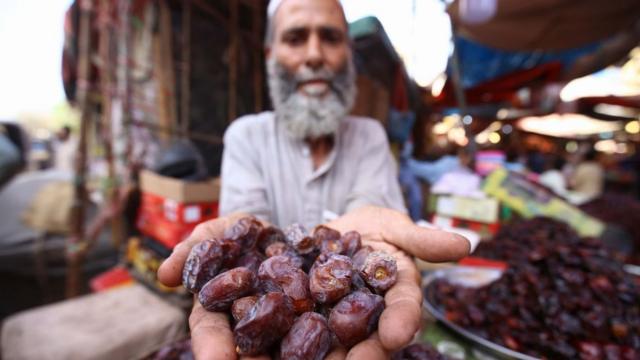 شخص يُمسك تمر بين راحتيه.