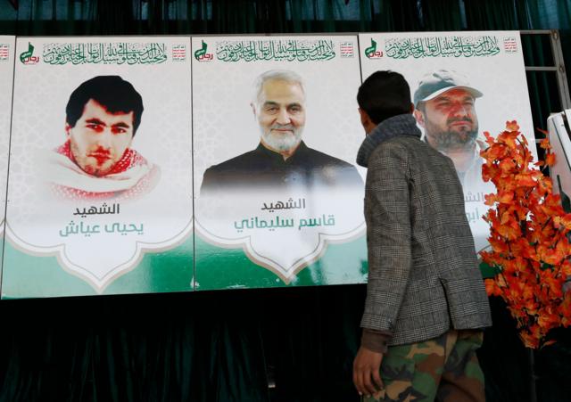 يمني يقف أمام صورٍ للقيادي السابق في حركة الجهاد الإسلامي الفلسطينية بهاء أبو العطا، والقائد السابق لفيلق القدس الإيراني قاسم سليماني، والقيادي العسكري السابق في كتائب عز الدين القسام يحيى عياش، خلال معرض