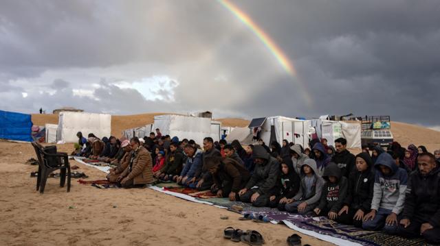 يظهر قوس قزح بينما يؤدي النازحون الفلسطينيون، صلاة عيد الفطر بجوار خيامهم التي أقيمت بالقرب من الحدود المصرية، في مخيم رفح بجنوب قطاع غزة
