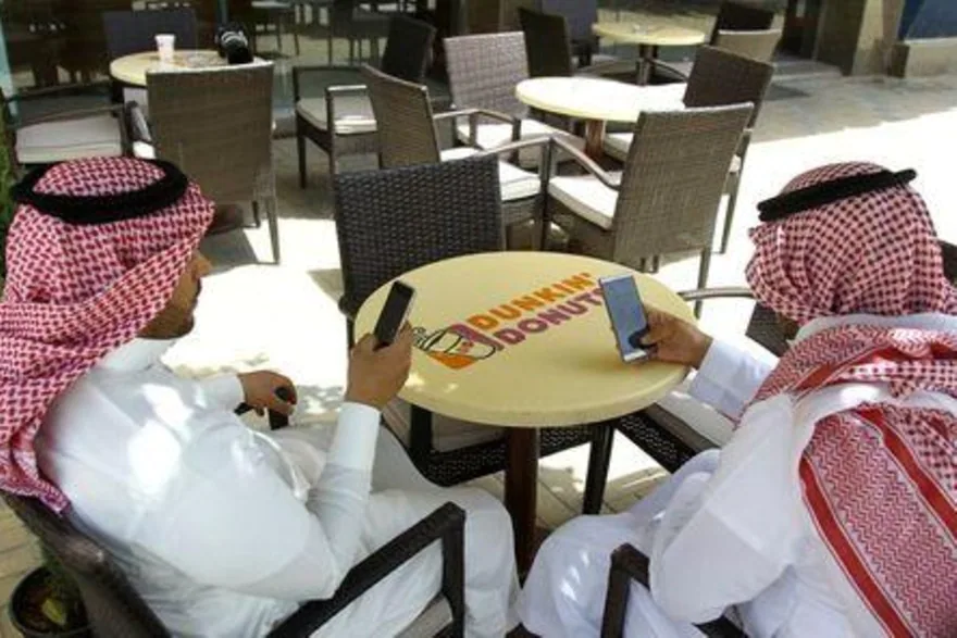سعوديان يطالعان هاتفيهما في مقهى بالرياض. صورة من أرشيف رويترز reuters_tickers