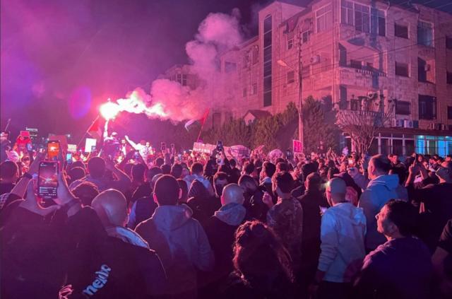 متظاهرون يحتجون ليلاً، دعماً للفلسطينيين في غزة، قرب السفارة الإسرائيلية في عمان، الأردن