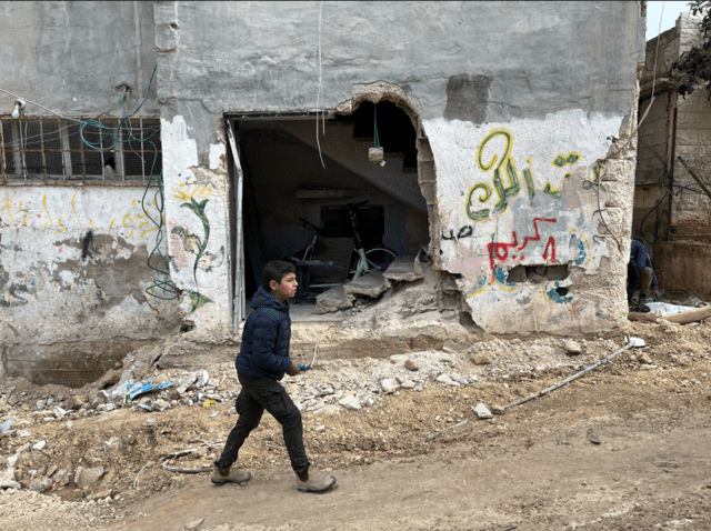 فتى فلسطيني يمشي بين الدمار في مخيم نور شمس