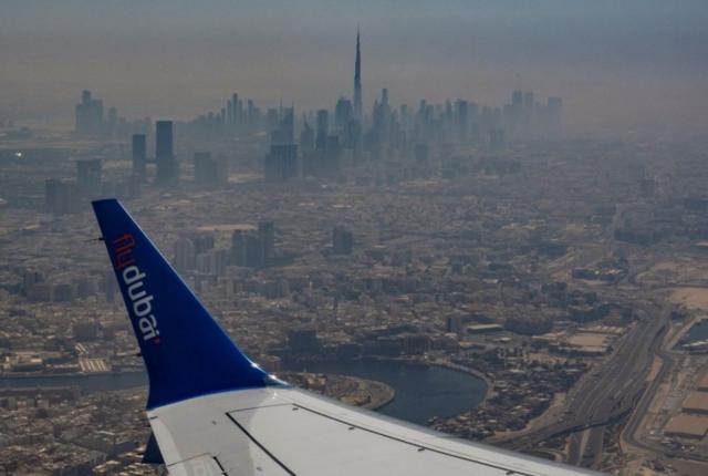 مشهد جوي لأفق دبي يظهر فيه جناح طائرة، وبرج خليفة كما يُرى من طائرة