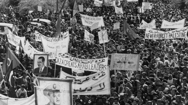 سكان غزة يرفعون صورناصر خلال مظاهرة بعد رحيل القوات الإسرائيلية من القطاع عام 1957.