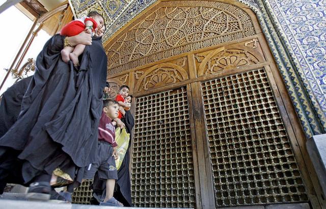 مجموعة من السيدات ترتدي عباءات سوداء بصحبة أطفال داخل موسى بن جعفر الكاظم