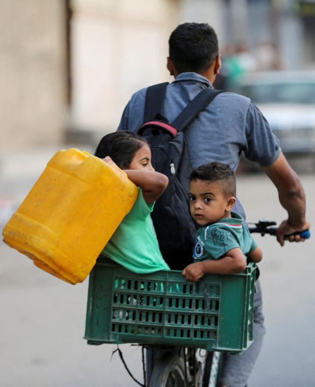 فلسطيني يركب دراجة مع أطفال مع متعلقاتهم أثناء فرارهم من رفح بسبب عملية عسكرية إسرائيلية، في رفح بجنوب قطاع غزة