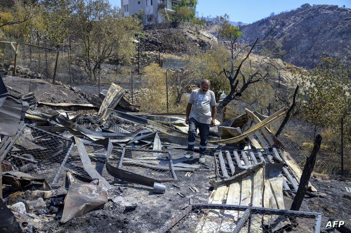 عبد الله أوزاتا، 43 عاما، يسير بين الأنقاض في موقع حظيرته المحترقة حيث نفقت حيواناته في حريق غابات في قرية سنجقلي في مقاطعة إزمير غربي تركيا في 18 أغسطس 2024. 